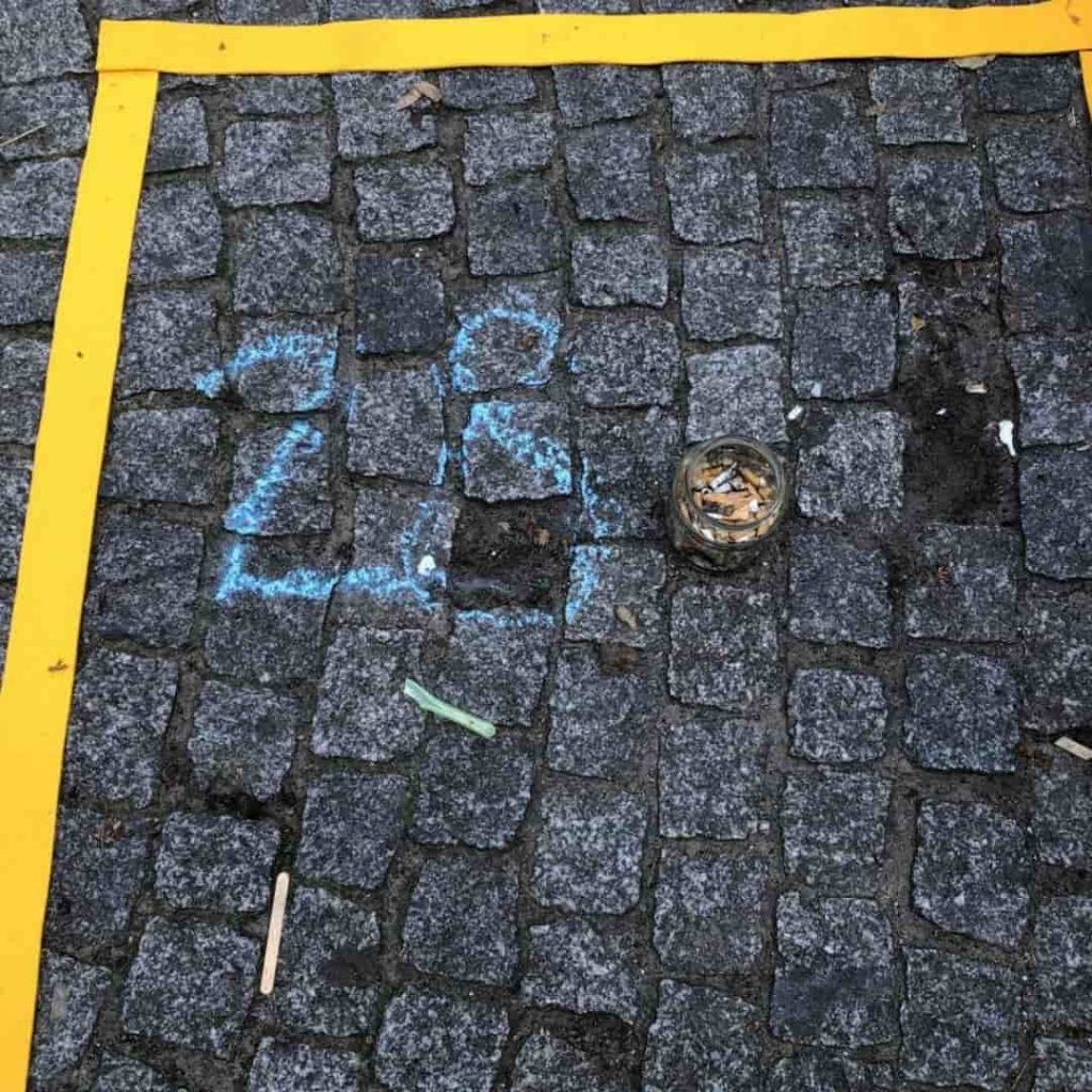 In einem gelben Quadrat ist die Zahl 28 mit Kreise aufgemalt und danebne liegen gesammelte Kippen